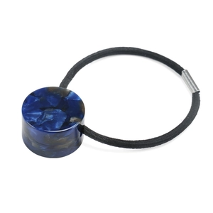 Detail view of navy blue marble acetate cylinder on a black high-elasticity hair scrunchie