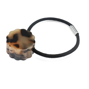 Detail view of a high-elastic hair tie featuring a tortoiseshell floral acetate ornament