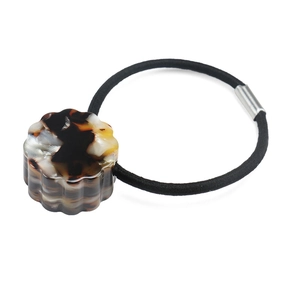 Detail of tortoiseshell patterned resin bead on a thick black elastic hair tie with silver link