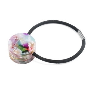 Detail of high-elasticity hair tie featuring a colorful marbled resin cylinder and metal buckle