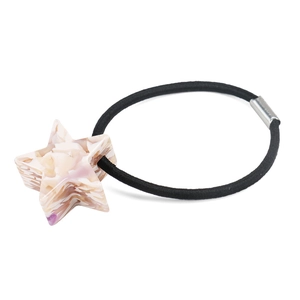 Dettaglio di un ciondolo a stella rosa marmorizzato su un elastico nero per capelli