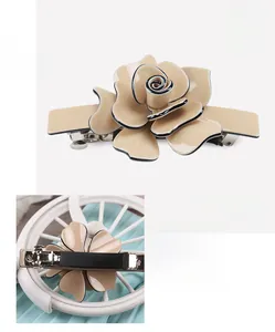 Detail view of acrylic camellia hair clip with black edges and spring clip mechanism