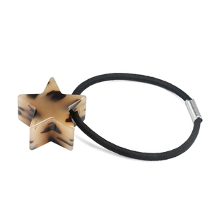 Dettaglio di stella in acetato tartarugato su un elastico per capelli nero lucido