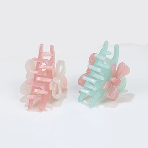 Pastel acrylic hair claws with 3D bows in pink and green, shown on a neutral background