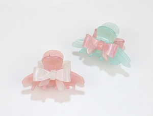 Detailed macro view of green and pink acrylic butterfly hair claws with pearlescent finish