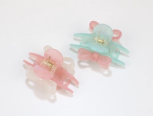 Close-up of pastel resin bow hair claw clips with gold metal springs in mint and pink