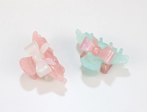 Close-up of pastel acrylic hair claws with cute bow accents and pearlescent finish