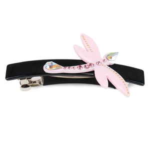 Detail of pink dragonfly hair clip with crystals and sparkling stones on black polished base