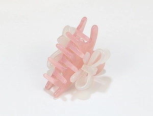 Detail view of pink and white acrylic hair claw clip with side bow decoration