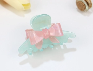 Close-up of translucent mint green acrylic hair claw with a soft pink resin bow detail