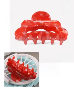 Detail showing red marble pattern hair claw clip with 8.5x4.5cm dimensions and glossy PVC finish