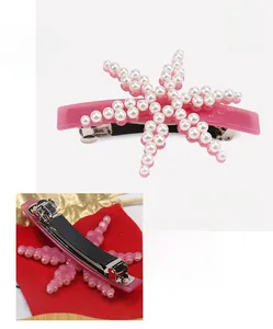 Detailed view of pink star-shaped hair clip with pearls and metal spring clip back