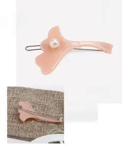 Vue détaillée de la pince à cheveux en acétate rose avec perle et pince métallique