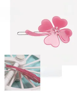 Detailed view of pink cellulose acetate clover hair clip with rhinestones and metal grip