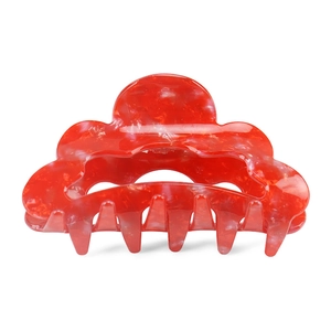 Detail view of the red wave-shaped hair claw clip with glossy marbled texture finish