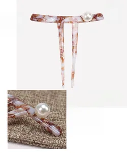 Detail of U-shaped marble acetate hair pin with large white pearl and polished finish