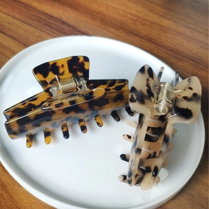 Detail of tortoise shell and ivory acetate hair claws with metal spring and multi-teeth design