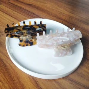 Detail view of large acetate claw clips in tortoise and pink marble on a white tray