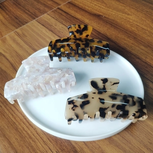 Three acetate hair claws with tortoiseshell and marble patterns on a wooden background