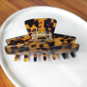 Detail view of tortoiseshell hair claw clip with sturdy gold metal spring on white plate