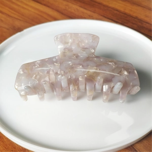 Macro shot of marble textured lavender acetate hair claw clip with golden metal spring