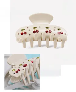 Macro detail of cream cellulose acetate hair claw with cherry rhinestone pattern