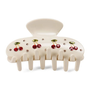 Creamy beige hair claw clip with crystal cherry patterns on a glossy resin surface