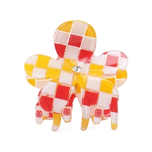 Dettaglio molletta a fiore per capelli con motivo a scacchi rosso giallo bianco e strass