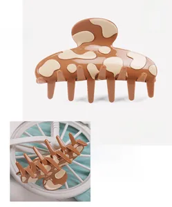 Detailed close-up of a brown and cream cow print hair claw clip made of high-quality acetate