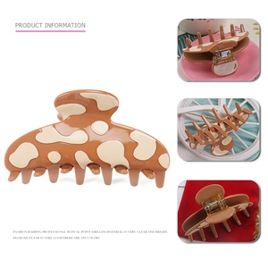 Macro detail of the cow print acetate hair claw clip showing various angles and metal spring