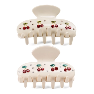 Close-up of cream acrylic hair claw clips with sparkling red cherry rhinestone embellishments