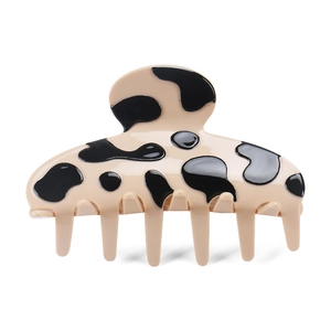 Detail of the large cow print acetate hair claw clip with a glossy finish and black spots