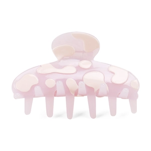 Detail of light pink acetate hair claw clip with cream cow print pattern and glossy finish