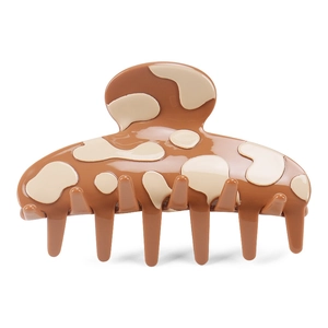 Macro view of large acetate hair claw clip with glossy brown cow print pattern