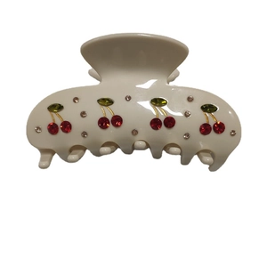 Creamy white hair claw clip with red cherry rhinestone patterns and gold detailing
