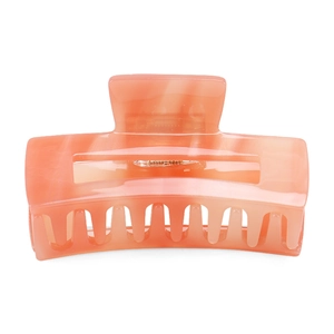 Detail view of square hollow hair claw in coral orange marbled acetate texture
