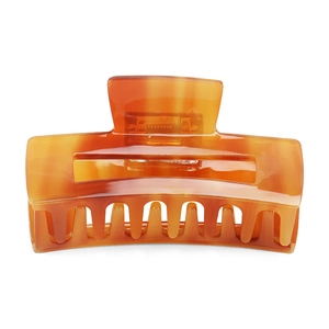 Detailed macro view of an amber tortoiseshell hair claw clip with a strong metal spring