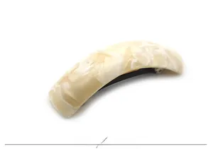 Detailed macro view of the cream and beige marbled acetate texture on the curved hair clip