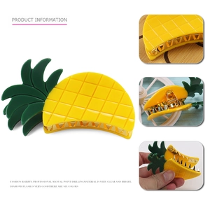 Detail view of yellow pineapple hair claw with green leaves and gold metal grip teeth