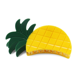 Detail view of a yellow acrylic pineapple hair claw clip with green leaves and gold teeth