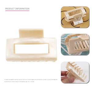 Macro detail of a medium square cream resin hair claw clip with pearl marble texture