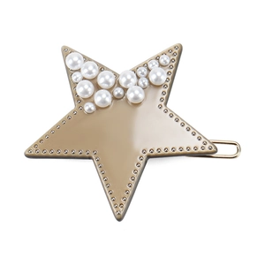 Detailed close-up of a star hair clip with acetate finish and inlaid pearls on a gold clip