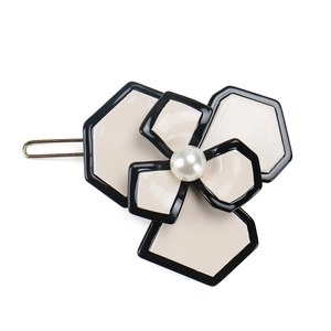 Detail of camellia flower hair clip with pearl center and elegant golden metal base