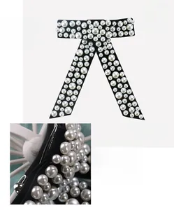 Detailed view of a black velvet bow hair clip with white pearl inlay and metal clip base