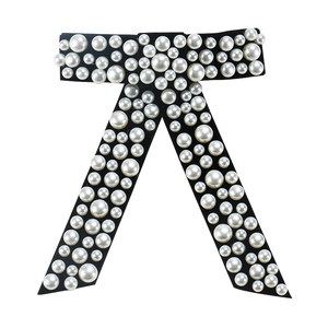 Detailed close-up of a vintage black velvet bow hairclip with elegant pearl embellishments