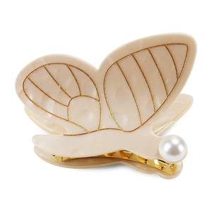 Détail de la pince à cheveux papillon en acétate avec nervures dorées et perle blanche