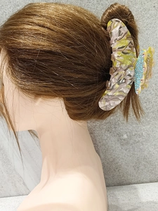 Detailed macro view of large acetate butterfly hair claw with rhinestones on hair bun