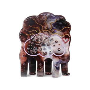 Detail of acetate cloud hair claw featuring celestial patterns and rhinestone accents