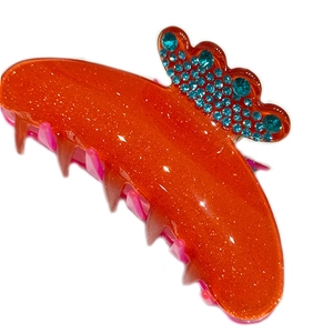 Close-up of orange glitter hair claw clip with blue rhinestones for elegant styling