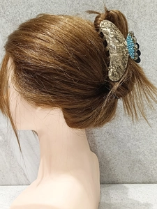Detail view of acetate tortoise hair claw with blue rhinestones on brown hair
